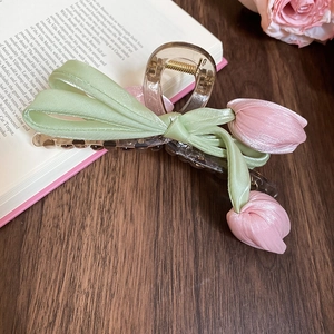 Detail of tulip hair claw clip with pink fabric flowers and green satin ribbons
