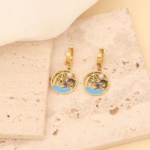 Detail of golden earrings with palm tree and blue enamel waves on a stone surface