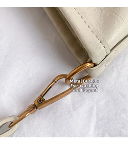 Macro shot of retro gold buckle hardware attached to off-white pebbled leather bag
