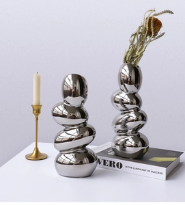 Detail of silver electroplated pebble ceramic vases with reflective mirror finish and dried flower