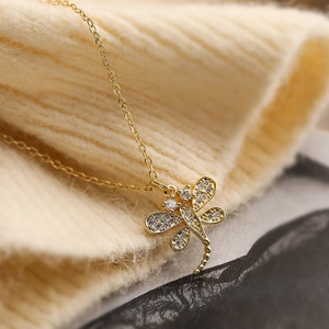 Exquisite gold-plated dragonfly pendant necklace with sparkling cubic zirconia on a knit background
