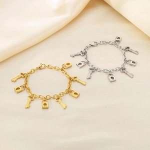 Detailed shot of key and lock pendants on gold and silver stainless steel bracelets
