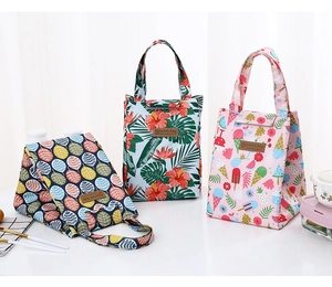 Detailed view of three insulated lunch bags with tropical and fruit patterns on a white table