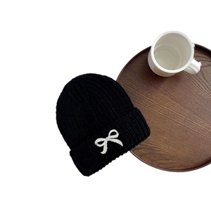 Black knitted winter hat for children featuring a delicate white embroidered bow detail