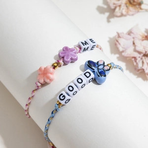 Handmade woven bracelets with ceramic flower, butterfly charms and letter beads detail