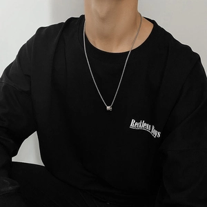 Silver titanium steel cylinder necklace pendant shown on male model neck with black sweater