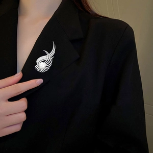 Détail d'une broche en forme d'aile avec perle et zircons sur revers de veste