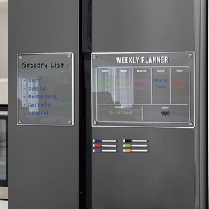 Macro detail of acrylic magnetic weekly planner and grocery list on a fridge door