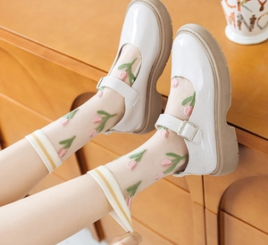 Détail de chaussettes transparentes à broderie tulipe et chaussures Mary Jane blanches