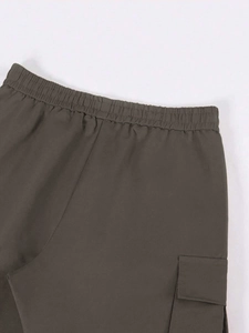 Dettaglio vita elastica e tasche cargo laterali su pantaloni da lavoro larghi dritti
