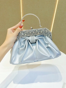 Macro view of silver pleated evening bag with sparkling rhinestone handle and clasp