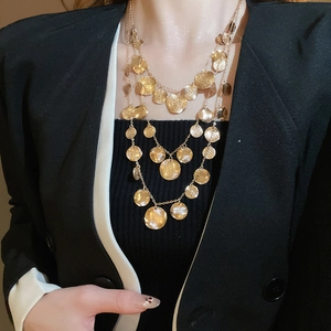Close-up of triple-layered gold coin necklace showing hammered metal texture on model
