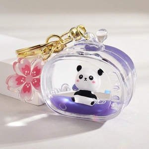 Close-up of panda liquid keychain with purple oil and sakura charm on a ring