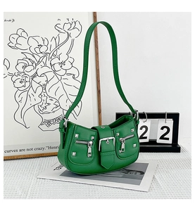 Close-up of green moon-shaped crossbody bag with silver studs and zipper detail