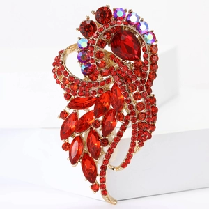 Vintage gold feather brooch with red rhinestones and iridescent gems on white stand