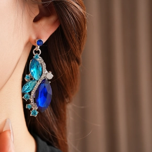 Detail of vintage diamond-studded rhombus earrings with deep blue crystals on model