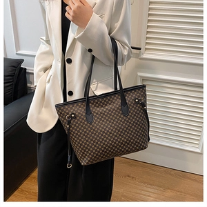 Detailed view of dark brown tote bag with geometric grid pattern and black leather straps