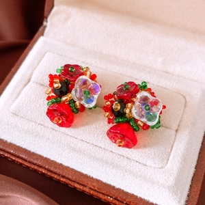 Close-up of handmade glass beaded flower earrings in red and green on a velvet box