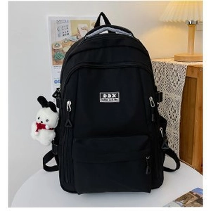 Detail of black multi-pocket school backpack with a cute white bunny plush charm