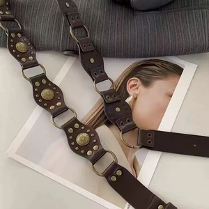 Vintage dark brown leather belt with bronze metal rings and studs on a textured background