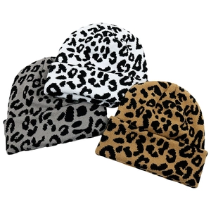 Detail of leopard print knitted beanies in white, grey and tan colors stacked on white background