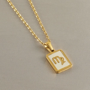 Macro shot of gold stainless steel Virgo zodiac pendant on white shell inlay O-chain