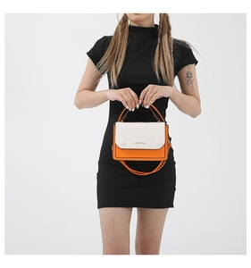 Détail d'un sac à main bicolore orange et blanc en cuir PU avec boucles décoratives rondes