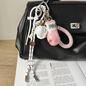 Dettaglio del portachiavi con guantone da boxe rosa e mazza da baseball su borsa