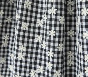 Detail of black and white gingham fabric with white floral embroidery and soft texture