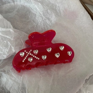 Close-up of red heart hair claw clip featuring sparkling rhinestones on white tissue paper
