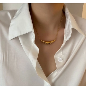 Gros plan d'un collier avec pendentif barre incurvée dorée porté sur une femme