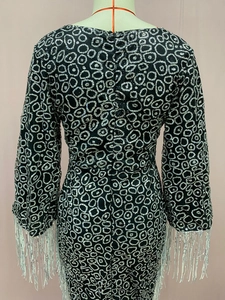 Detail of black sequined dress back featuring long sleeve tassels and a hidden zipper