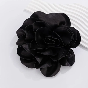 Close-up of a handcrafted black satin rose brooch with detailed layered fabric petals