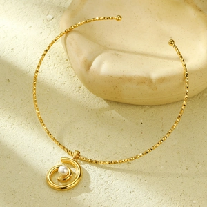 Detail of gold collar necklace with spiral pendant and a white pearl center