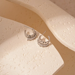 Elegant silver C-shape huggie earrings with cubic zirconia inlay on stone surface