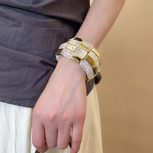 Close-up of a wide layered bracelet with gold metal and marble resin blocks on wrist