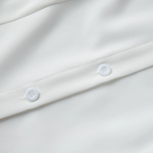 Macro detail of white twill fabric texture and classic four-hole buttons on sleeveless dress