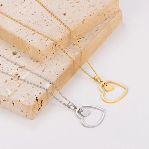 Gold and silver stainless steel layered double heart pendant necklaces on a stone