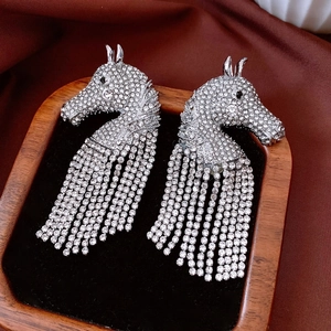 Detailed view of silver horse head tassel earrings with sparkling rhinestones on velvet