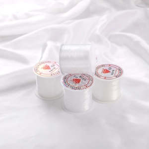 Rolls of clear nylon thread for jewelry making on white silk fabric background