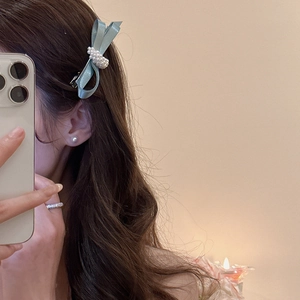Detail of light blue silk bow hair clip with white pearl center on model