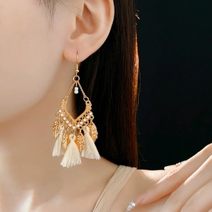 Model wearing vintage gold leaf earrings with beige tassels and white beads detail