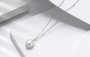 Detail of single white freshwater baroque pearl pendant on a delicate silver chain