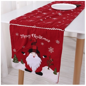 Close-up of red Christmas table runner with white snowflake patterns and Santa Claus appliqué