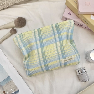 Close-up of yellow and light blue checkered cotton makeup bag with brand logo label