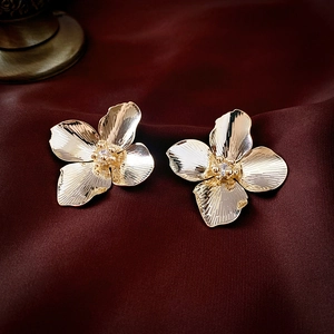 Elegant gold flower stud earrings with central zircon on luxury red silk background