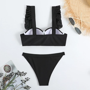 Flat lay of black two-piece bikini featuring ruffled shoulder straps and summer accessories