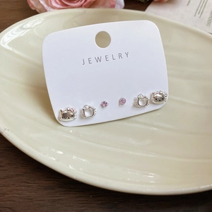 Close-up of Hello Kitty cat stud earrings and pink zircon jewelry set on a ceramic tray