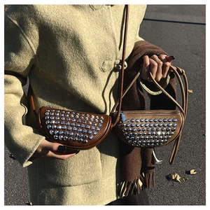 Close-up of saddle bags with silver rivets and pebbled leather on a wool coat