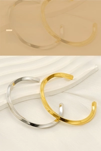 Macro shot of polished C-shaped twisted diamond pattern bangle in gold and silver finish